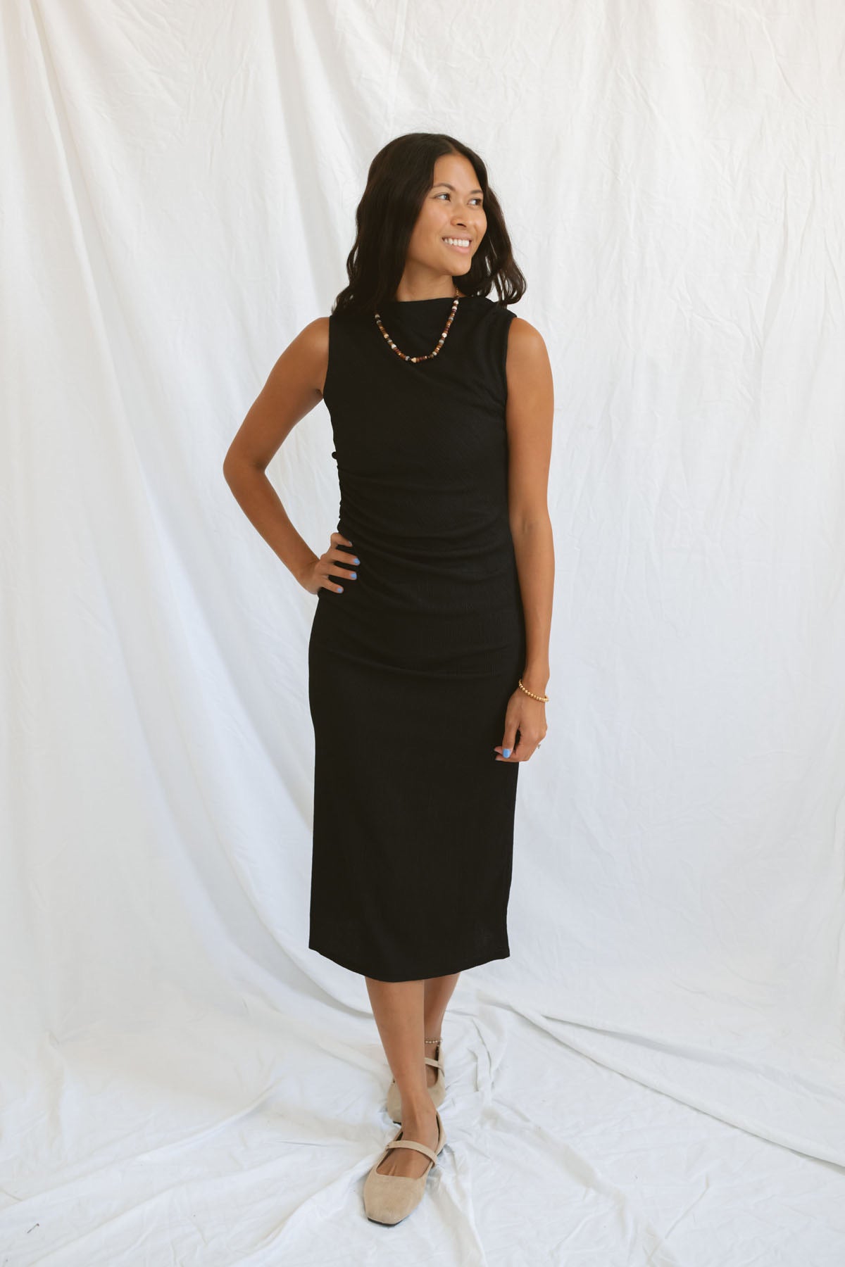 Model wearing pleat detail black midi dress.