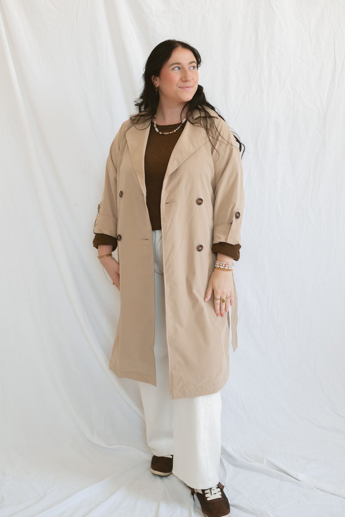 Model wearing the khaki long sleeve trench cost with buttons and belt.