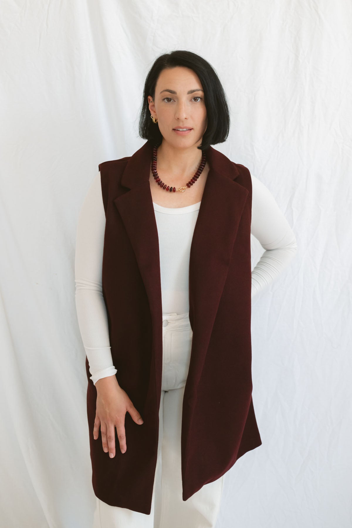 Model wearing the open sleeveless notched collar vest in burgundy color.