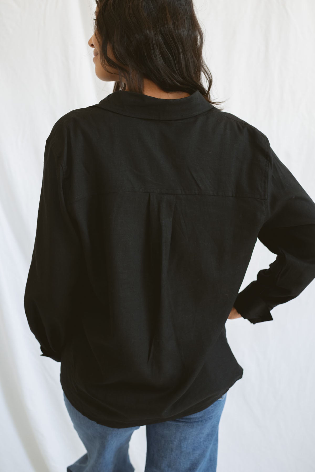 Model wearing classic black button up styled fully buttoned with a classic denim.