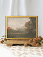 A richly atmospheric landscape featuring an open meadow framed by trees dressed in warm autumn hues. Soft light, layered textures, and painterly brushwork evoke the peaceful beauty and quiet elegance of the changing seasons.