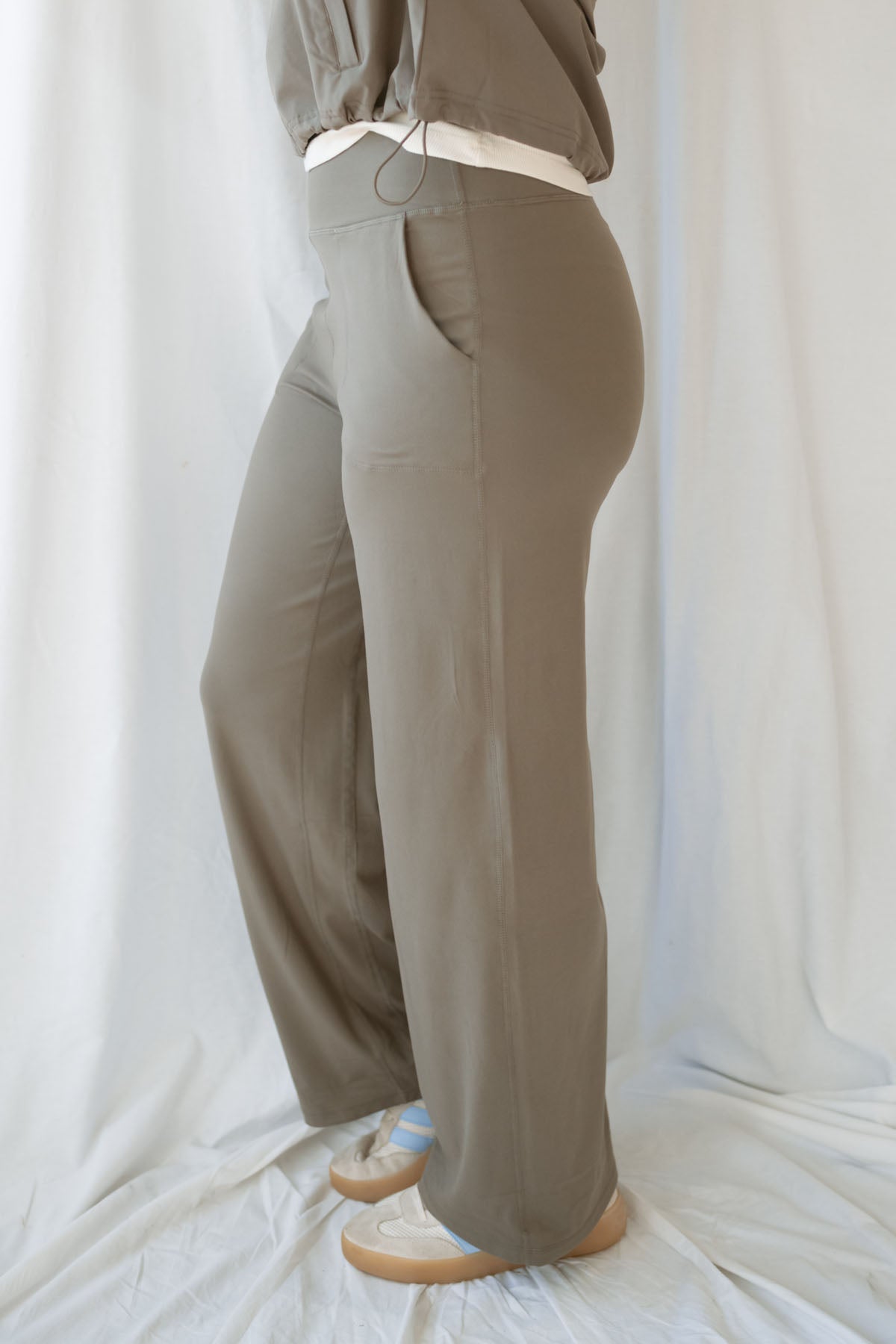 Side Picture of Woman wearing truffle high-waisted wide-leg pants with deep side pockets and a matching cropped jacket.