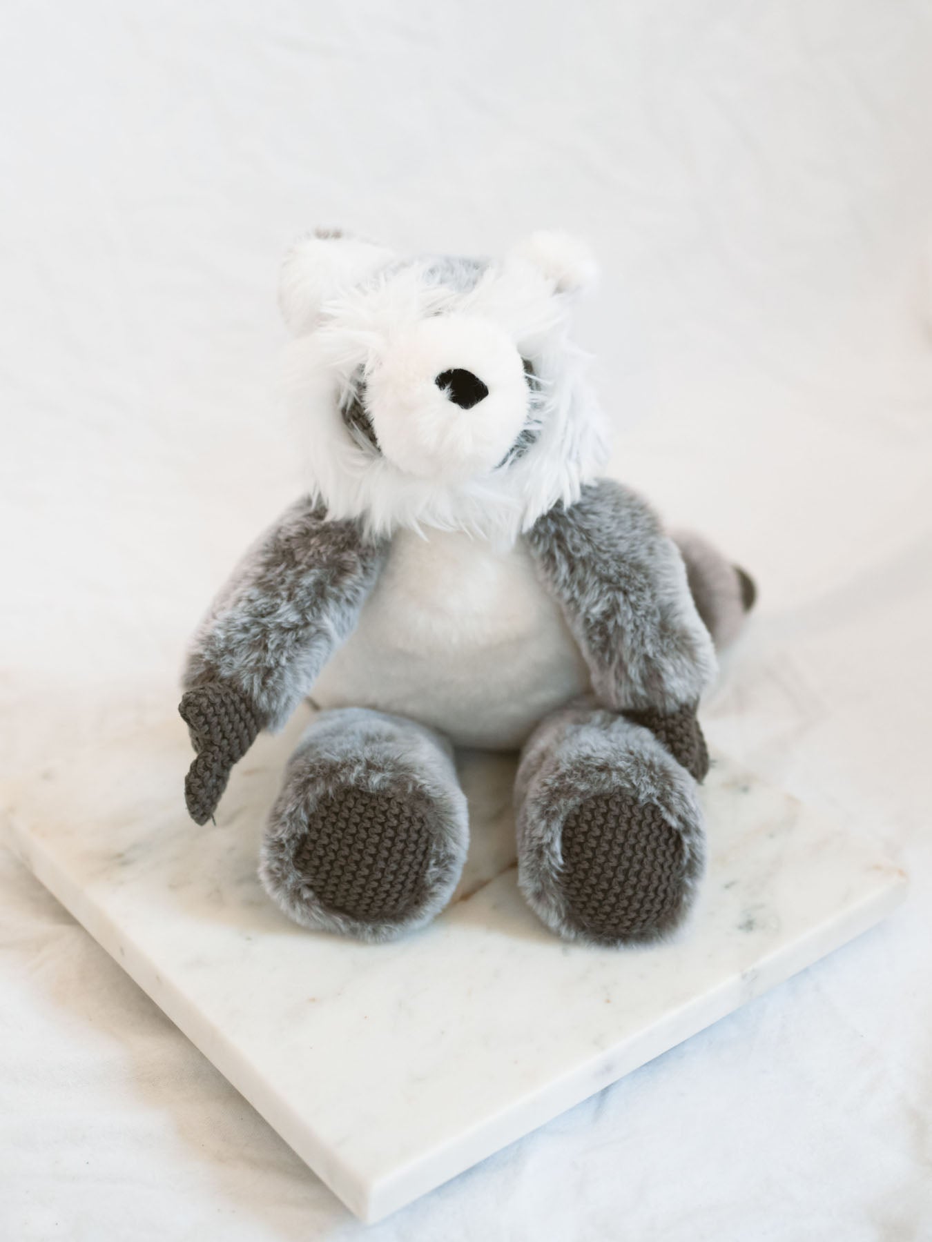 Plush raccoon toy on a marble tray with White background 