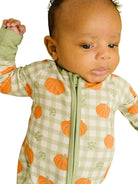 Baby wearing a soft sage gingham bamboo footie with an allover pumpkin print on a white background