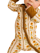 close up picture of a baby wearing a sunflower and stripe zip sleeper on white background