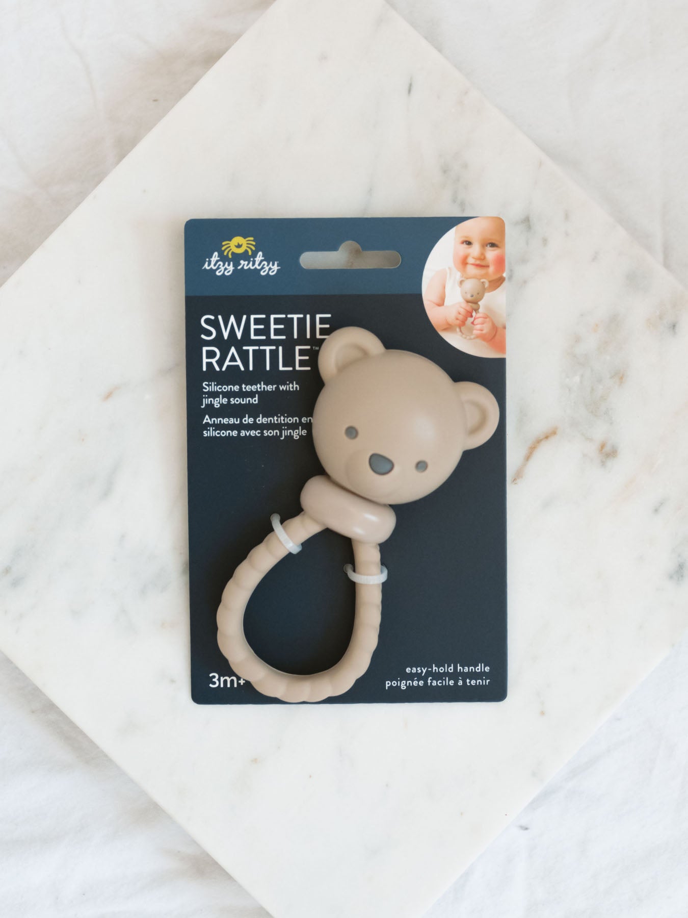 brown teething silicone rattle toy for babies laying on a marble tray with white background 