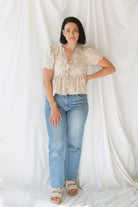 Model wearing the Floral Embroidered Front Tie Scalloped Peplum Top. Sweet and classy, this top can be dressed up easily or kept casual depending what you pair with it. 