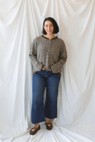 Model wearing a deep brown and tan henley button sweater. 