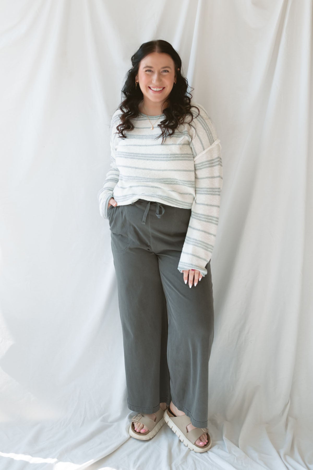 Model wearing cotton wide leg pants with drawstring waistband. Model has the pants styled with a lightweight sweater, but they can be paired with other basics tees or blouses. 