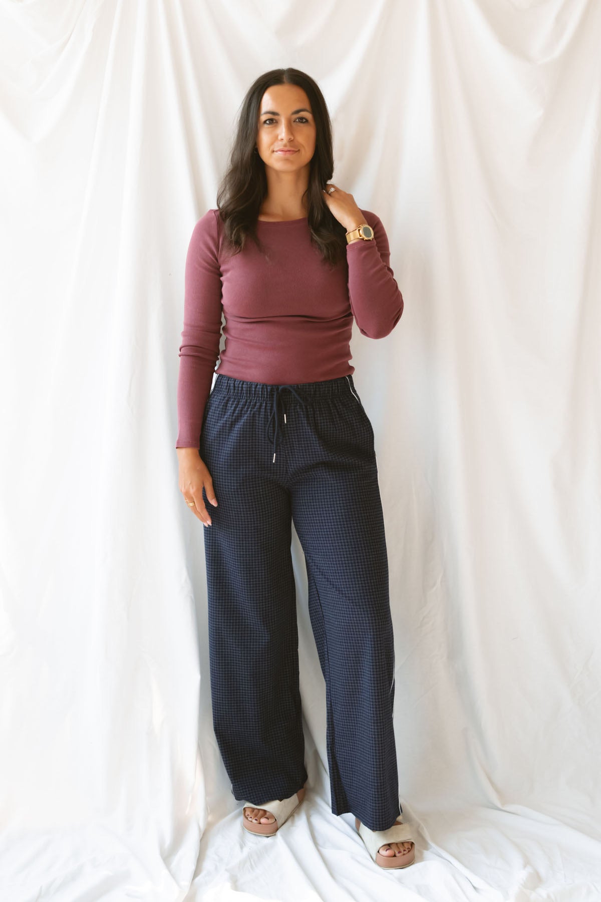 Model wearing ribbed long sleeve top with boat style neckline. Model has top styled with our navy checkered wide leg pants, but could be paired with a variety of bottoms. 
