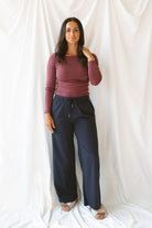 Model wearing ribbed long sleeve top with boat style neckline. Model has top styled with our navy checkered wide leg pants, but could be paired with a variety of bottoms. 