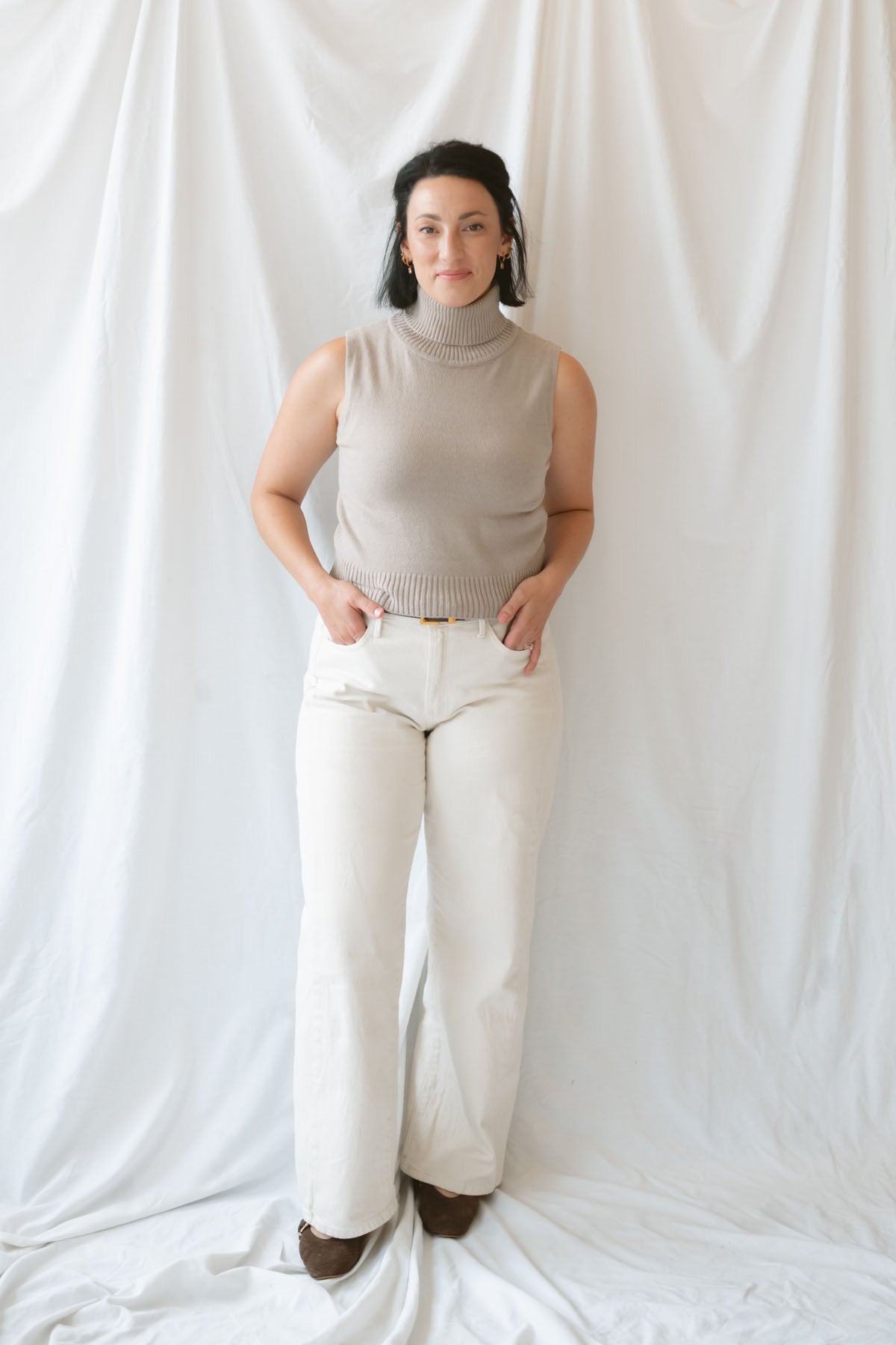 Model wearing the soft knit sleeveless turtleneck top. 