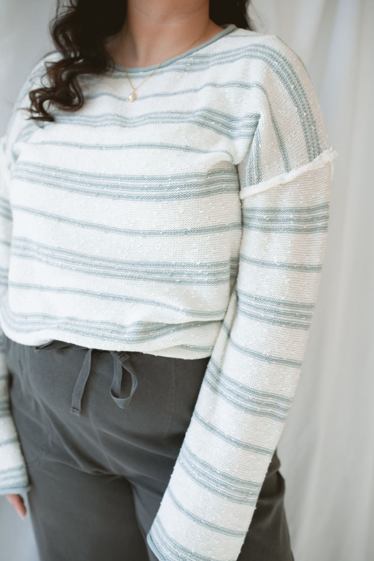 Model wearing the textured striped oversized sweater. Lightweight enough to wear now and into the next season. Paired with the Mila wide leg pants, this outfit is comfy, casual, and still put together.