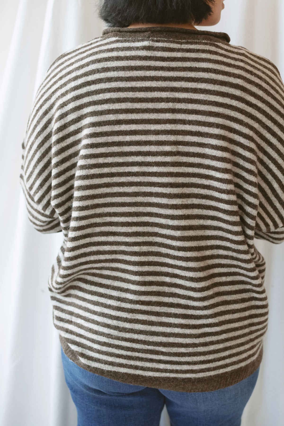 Model wearing a deep brown and tan henley button sweater. 