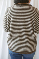 Model wearing a deep brown and tan henley button sweater. 