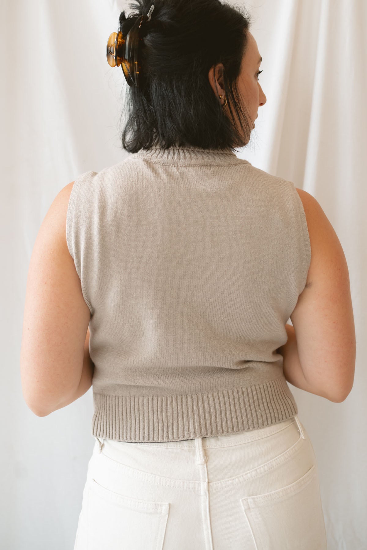 Model wearing the soft knit sleeveless turtleneck top. 