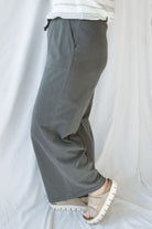 Side view of model wearing cotton wide leg pants with drawstring waistband. Model has the pants styled with a lightweight sweater, but they can be paired with other basics tees or blouses. 