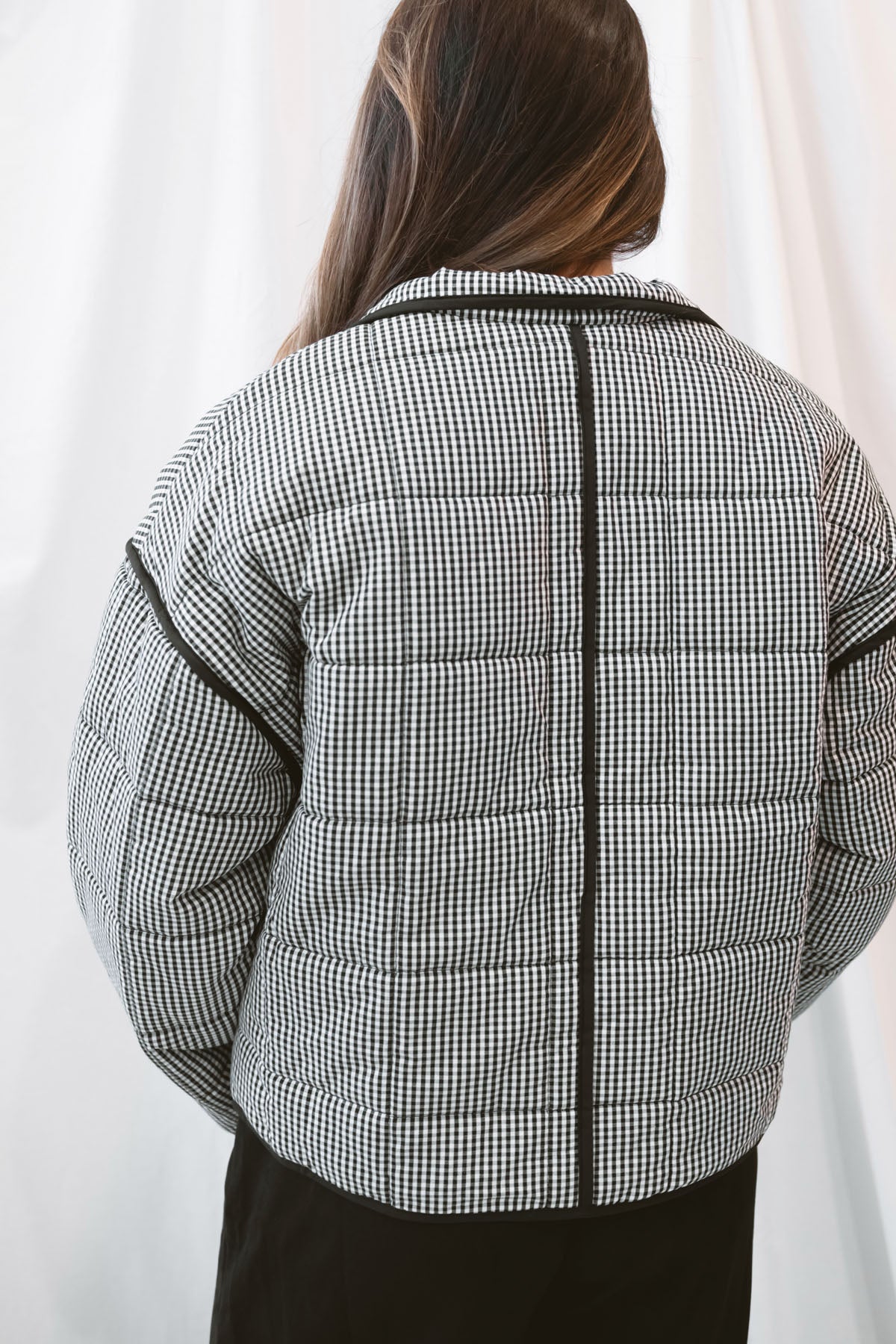 Black gingham quilted jacket for women featuring a classic checked pattern, textured quilted construction, and versatile everyday layering design.