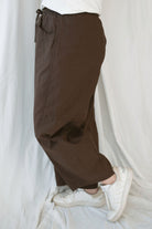 Model wearing the drawstring barrel style pant in coffee bean brown. 