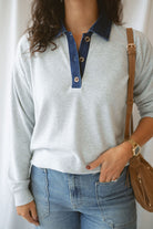 Model wearing pullover top in heather grey with denim collar detail.
