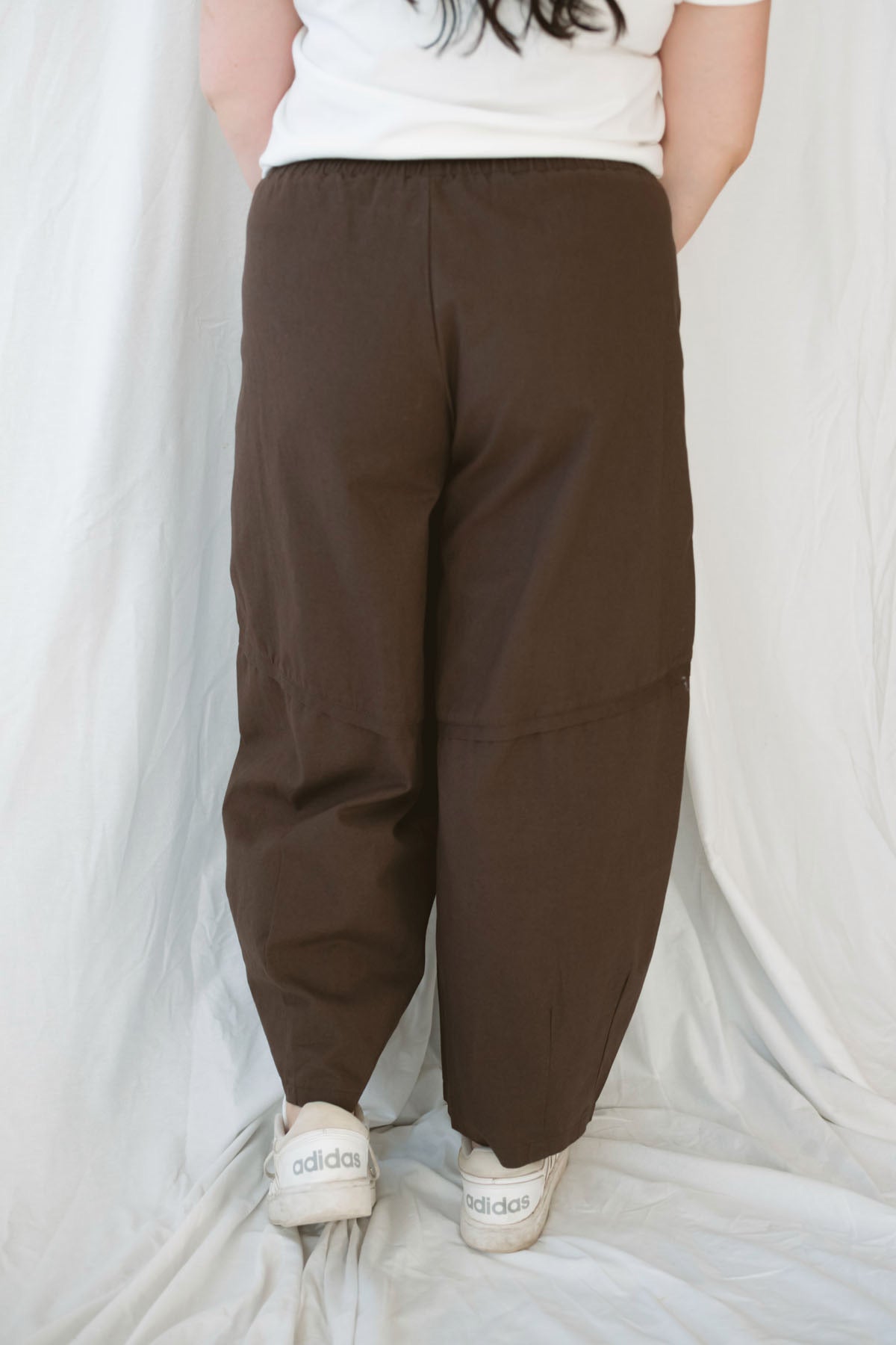 Model wearing the drawstring barrel style pant in coffee bean brown. 