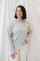 Model is wearing solid heather grey crew neck sweater. Styled with cream twist barrel pants. 