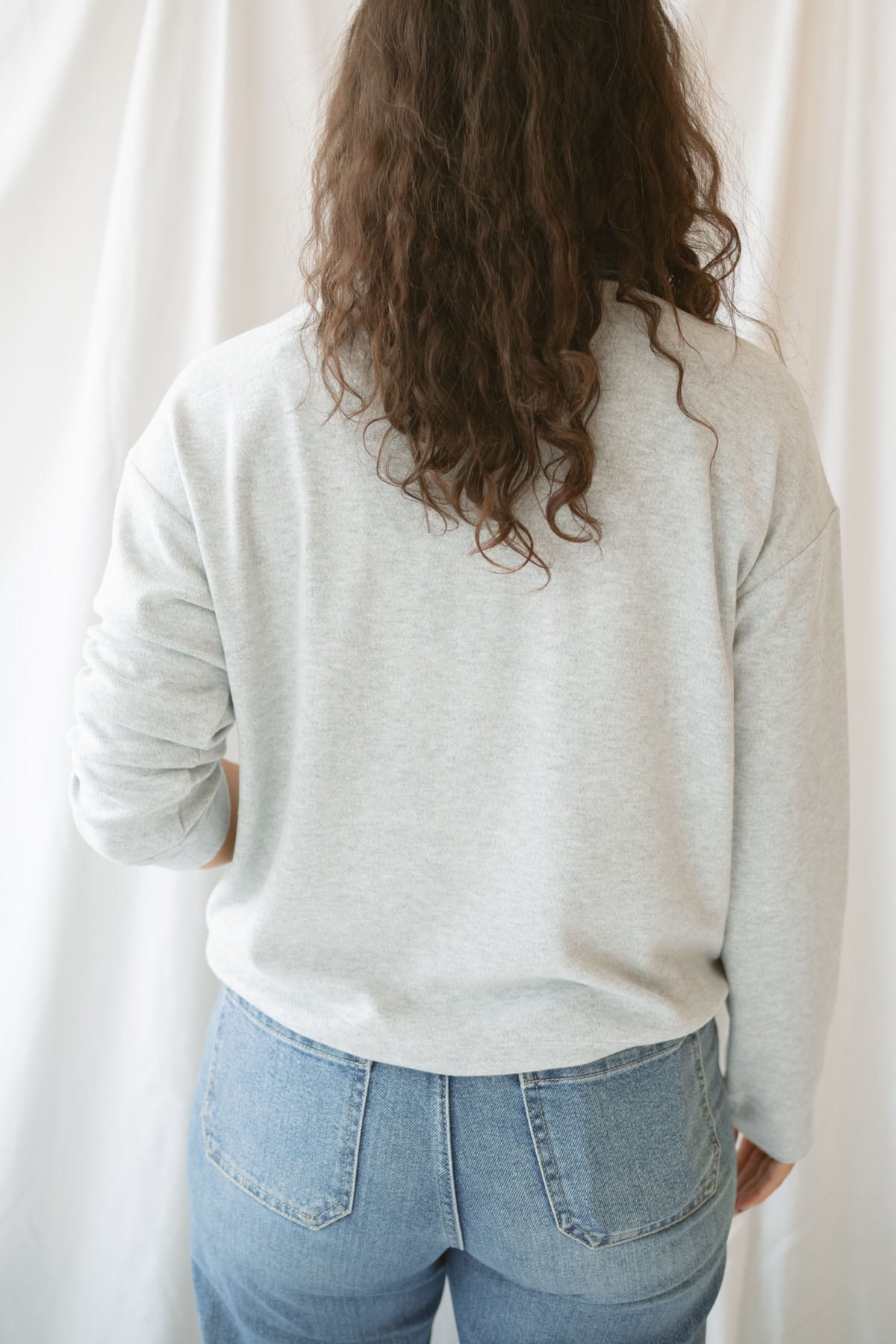 Model wearing pullover top in heather grey with denim collar detail.