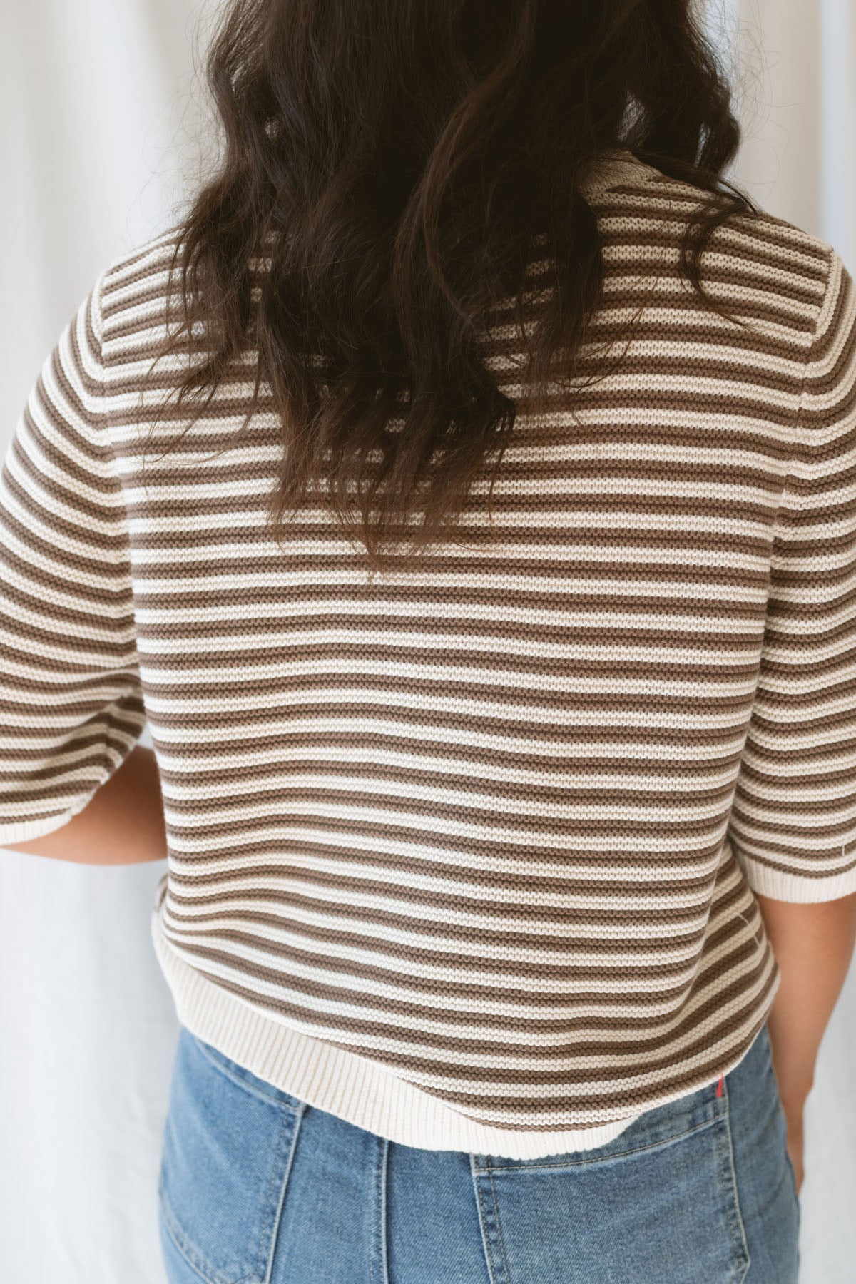 Back view of model wearing the textured stripe crew neck half sleeve top.