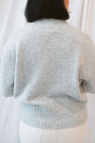 Model is wearing solid heather grey crew neck sweater. Styled with cream twist barrel pants. 