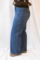 Dark wash stretch barrel-leg jeans for women featuring a subtle curved leg silhouette, twisted seam detailing, and a modern relaxed denim design.