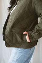 Model is wearing the lapel collar quilted jacket in olive. 