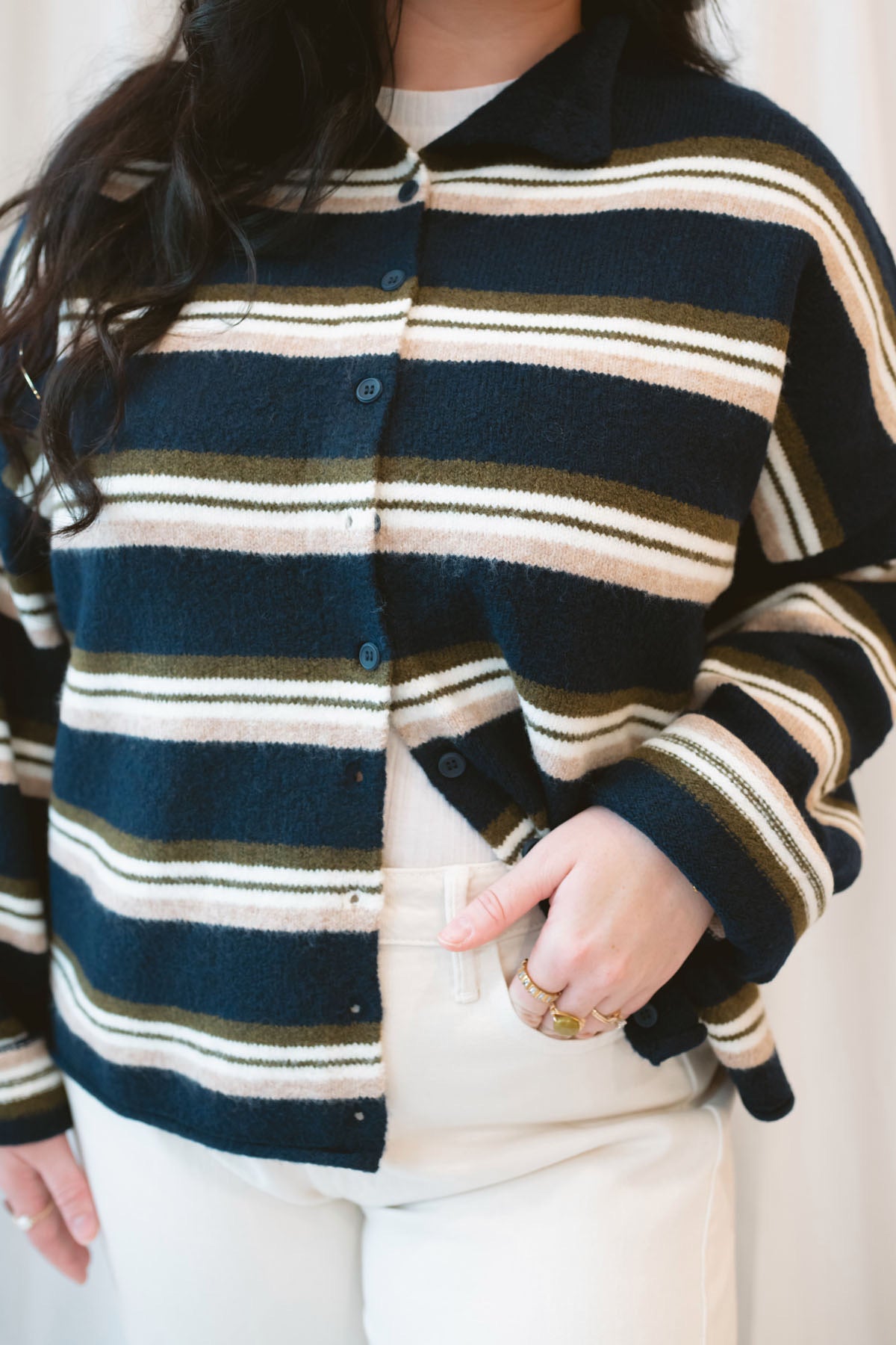 Model wearing navy stripe and multi colored button up cardigan. 