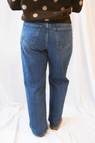 Dark wash stretch barrel-leg jeans for women featuring a subtle curved leg silhouette, twisted seam detailing, and a modern relaxed denim design.