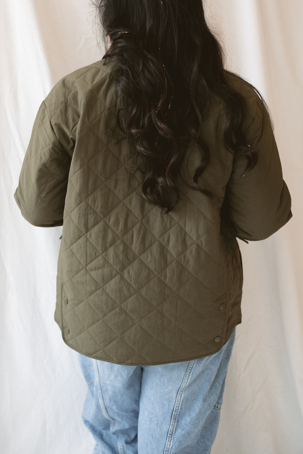 Model is wearing the lapel collar quilted jacket in olive. 