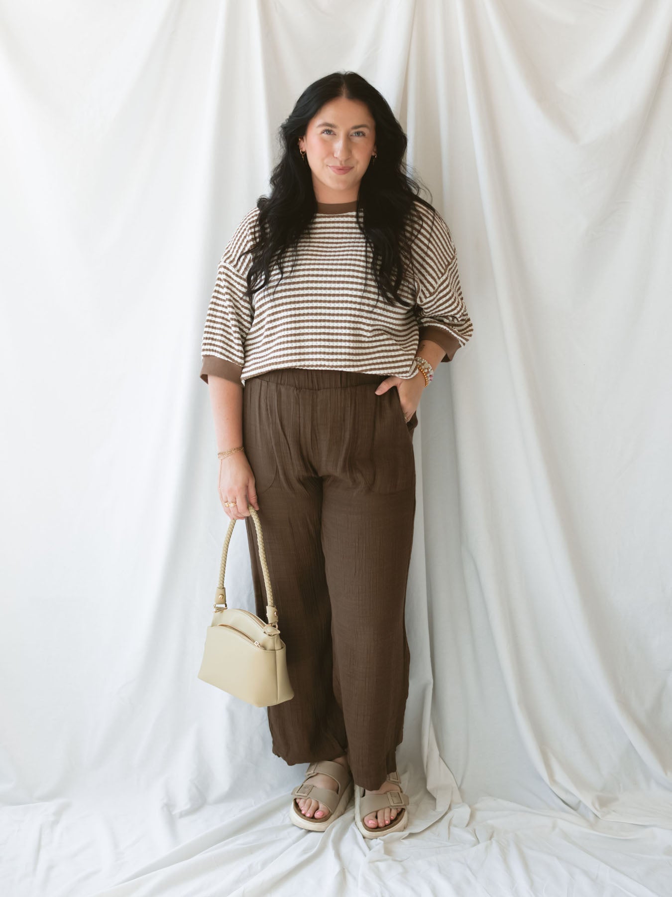 Model wearing brown linen blend pants with elastic waistband. 