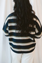 Model wearing navy stripe and multi colored button up cardigan. 