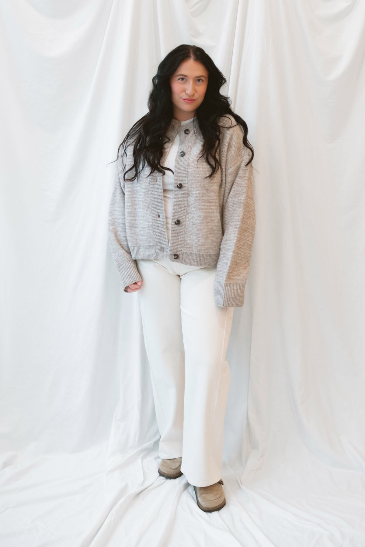 Model wearing boxy fit button up cardigan in latte tan. 