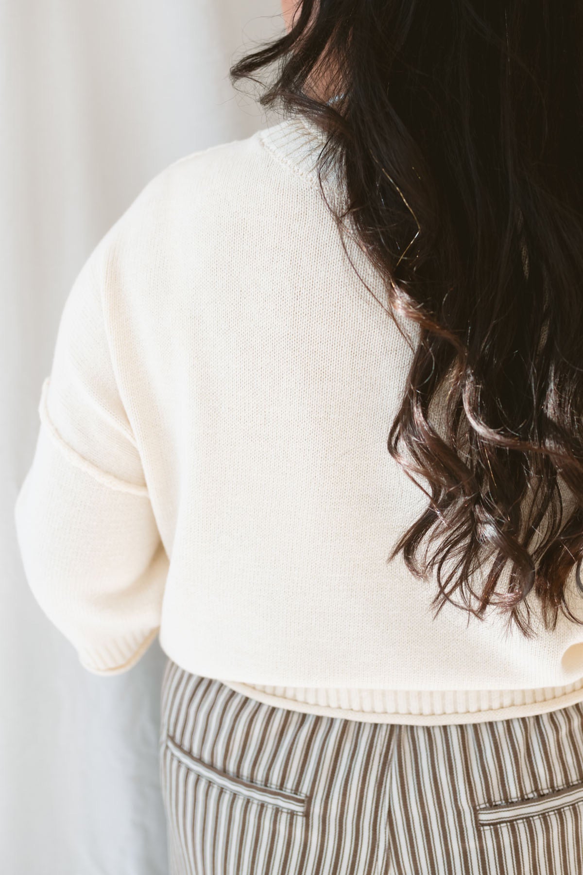 Back view of model wearing the drop sleeve exposed seam sweater short sleeve top. This top is very versatile, styling it during warm months with shorts of any kind and in the cooler months with long pants and eventually layering under jackets and blazers. 