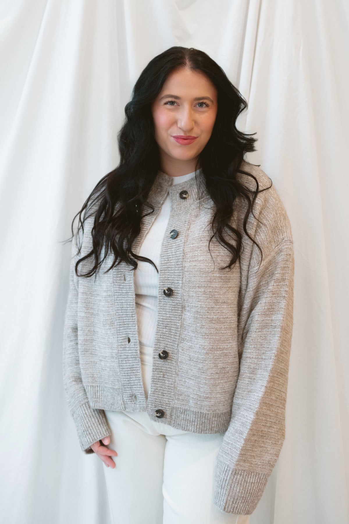Model wearing boxy fit button up cardigan in latte tan. 