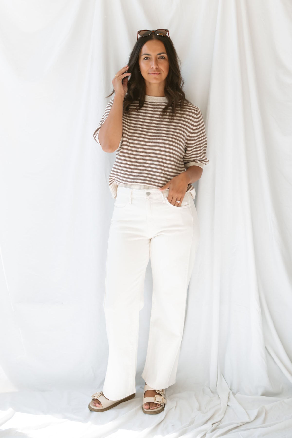 Model wearing the high rise stretch barrel denim pants in off white. 
