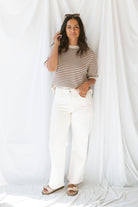 Model wearing the high rise stretch barrel denim pants in off white. 