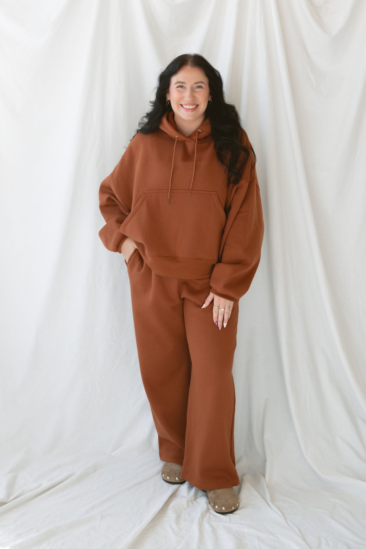 Model is wearing the oversized rust colored hoodie sweatshirt. 