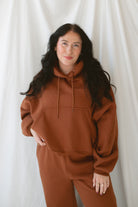 Model is wearing the oversized rust colored hoodie sweatshirt. 