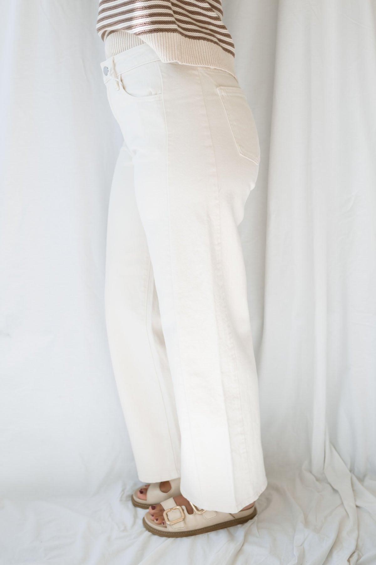 Model wearing the high rise stretch barrel denim pants in off white. 