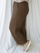 Side view of model wearing brown linen blend pants with elastic waistband. 