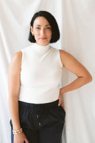 Model wearing the ribbed sleeveless high neck top in off white. A staple for your wardrobe from season to season. 