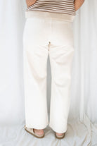 Model wearing the high rise stretch barrel denim pants in off white. 