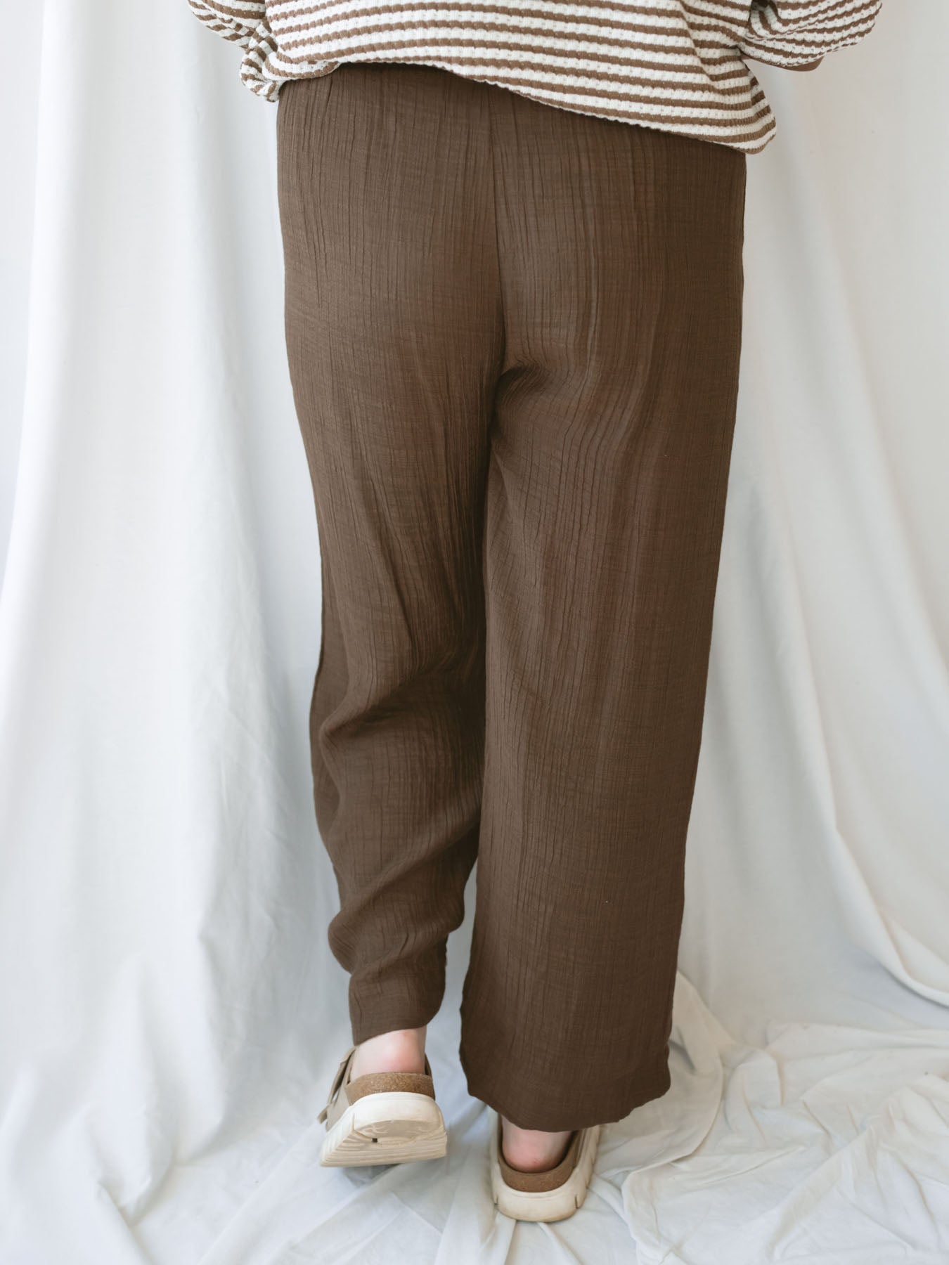 Back view of model wearing brown linen blend pants with elastic waistband