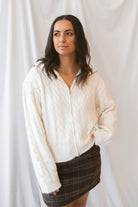 Madison High Neck Cable Fuzzy Knit Zip Up Cardigan in Cream featuring a high neckline, textured cable knit pattern, and zip-front closure.