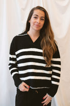 Black striped knit sweater top for women featuring a collared V-neckline, contrasting trim, and classic preppy-inspired design for elevated everyday styling.